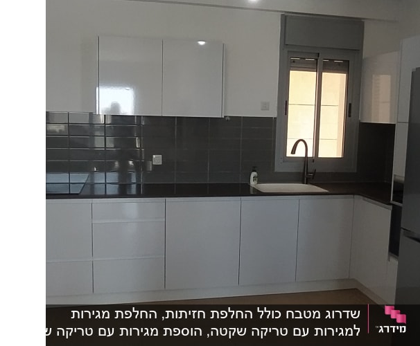 מטבח מודרני עם ארונות לבנים וכיור ליד חלון